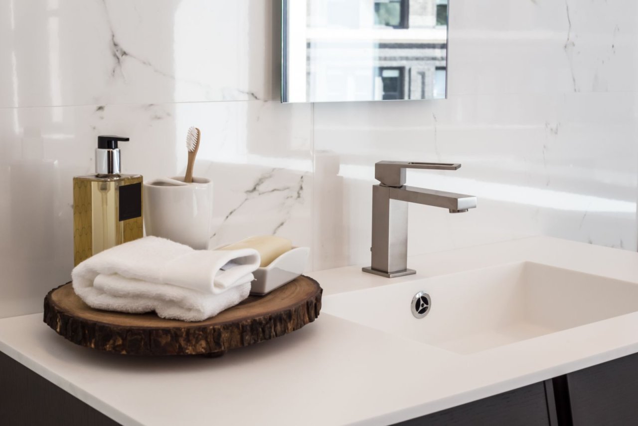 Badezimmer mit weißem Waschtisch und Metallarmatur